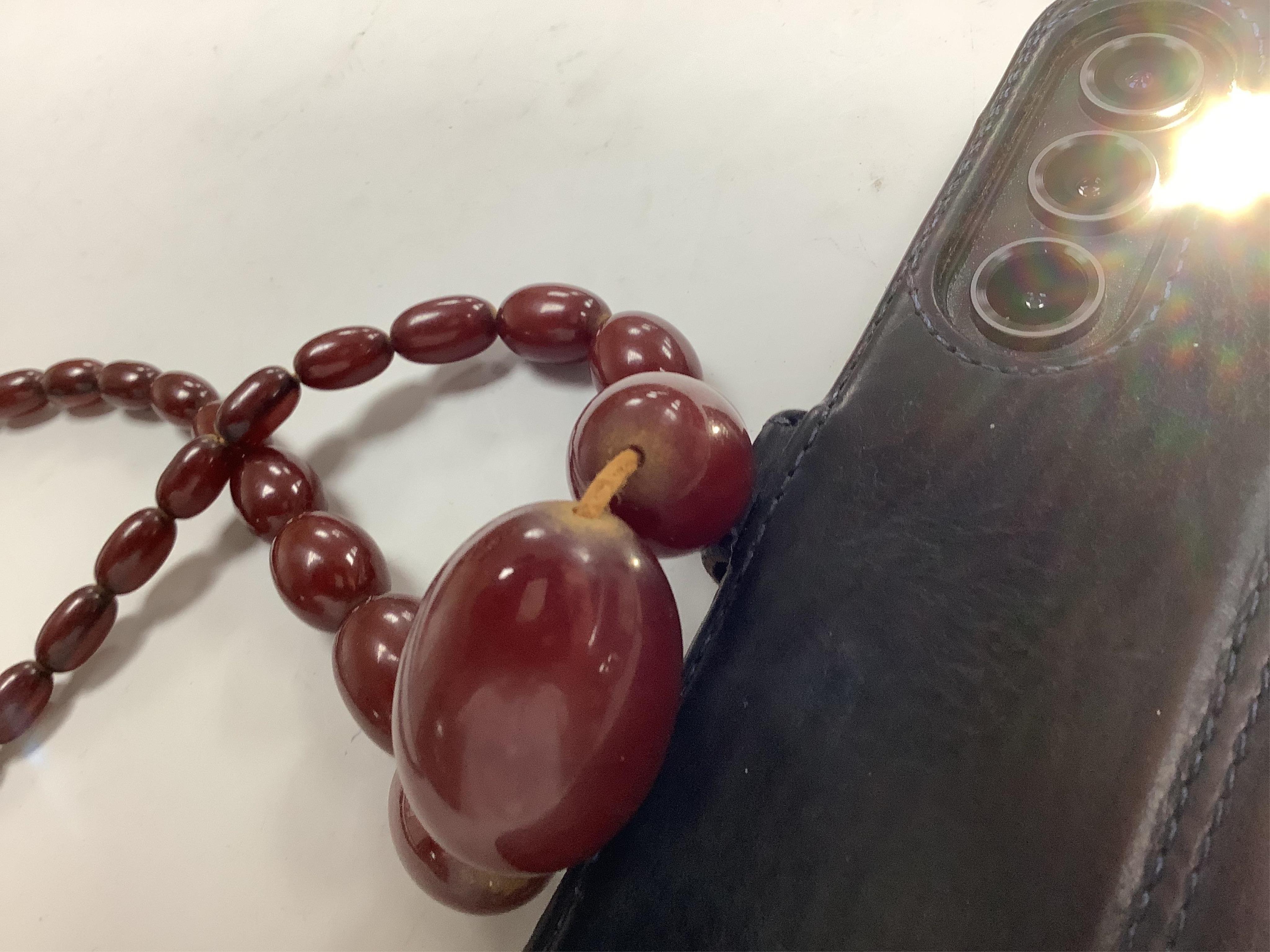 A cherry-coloured bakelite 'amber' necklace, composed of graduated oval beads measuring approximately 1.1-3cm, length 76cm, gross weight 66 grams, Condition: good, minor wear